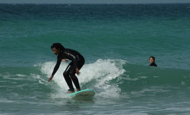 nino en una tabla surfeando y otro mirandole